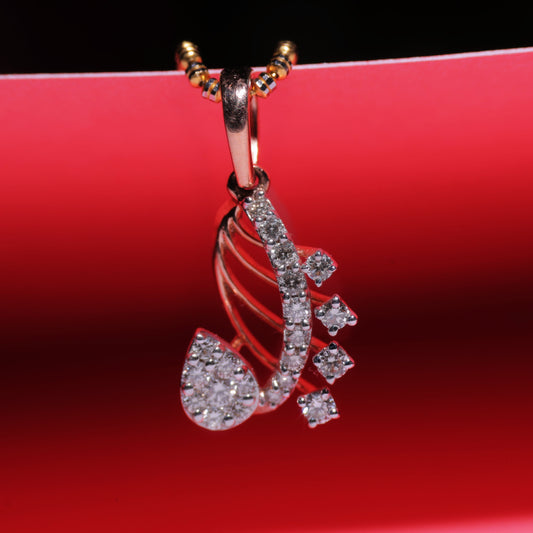 Rose gold paisley-shaped pendant by jnjbymadhuri, featuring intricate design with embedded white stones, displayed on a vibrant red background with golden chain loops.