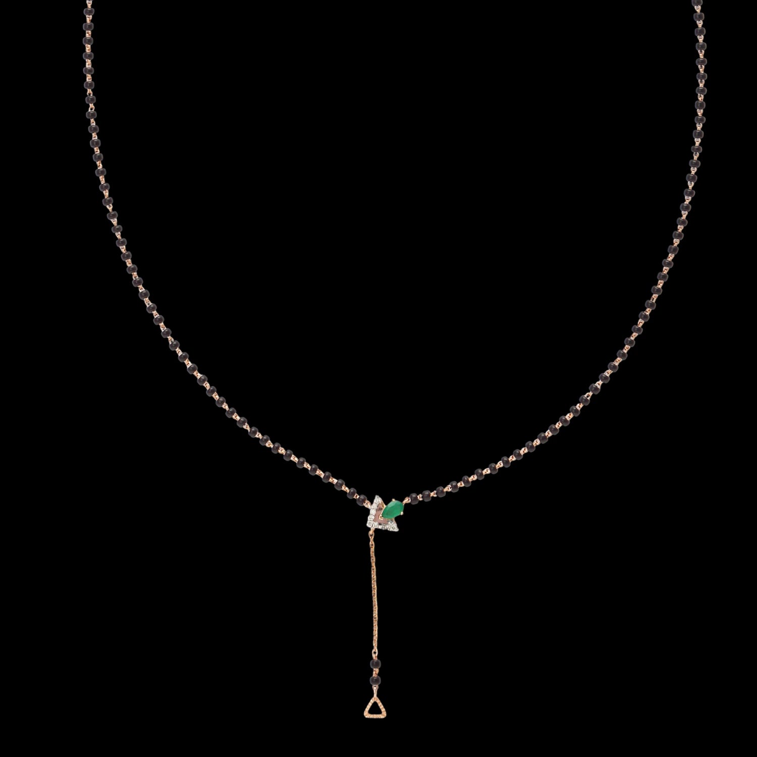 Elegant jnjbymadhuri mangalsutra set against a black background, featuring a delicate black bead chain accented with a striking emerald green stone centerpiece and a refined gold drop pendant, blending traditional symbolism with modern sophistication.