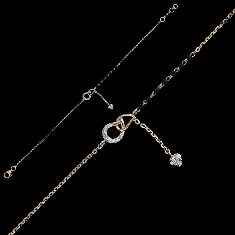 Contemporary mangalsutra bracelet in dual-tone gold, featuring a circular diamond-studded charm with a dangling heart pendant and traditional black bead detailing. A chic fusion piece by jnjbymadhuri.