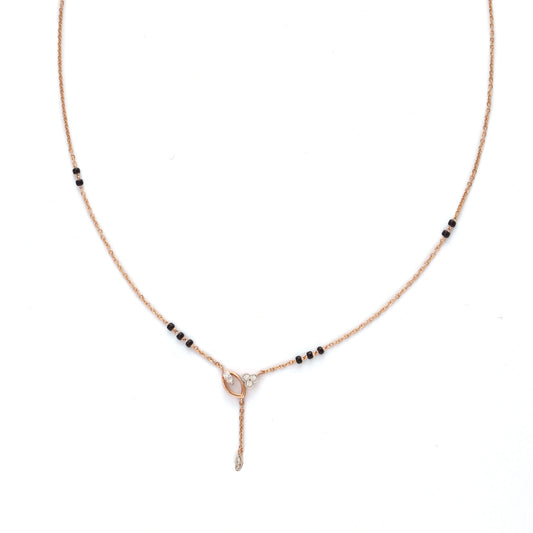 Minimalist mangalsutra with a delicate rose gold chain, accented by small black beads and featuring a central knot-like pendant with a vertical drop element, displayed on a white background.