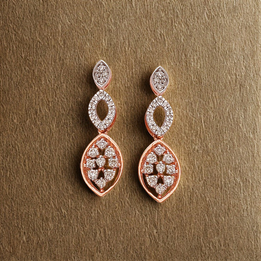 "Elegant rose gold drop earrings by jnjbymadhuri, featuring a dual marquise-shaped design with embedded white stones, beautifully displayed on a textured gold background."