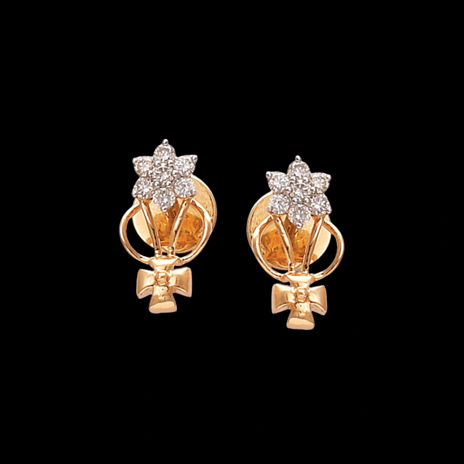 gold stud earrings featuring a floral diamond cluster at the top, with a gold ribbon-like design and bow-shaped detail at the bottom — displayed on a black background.
