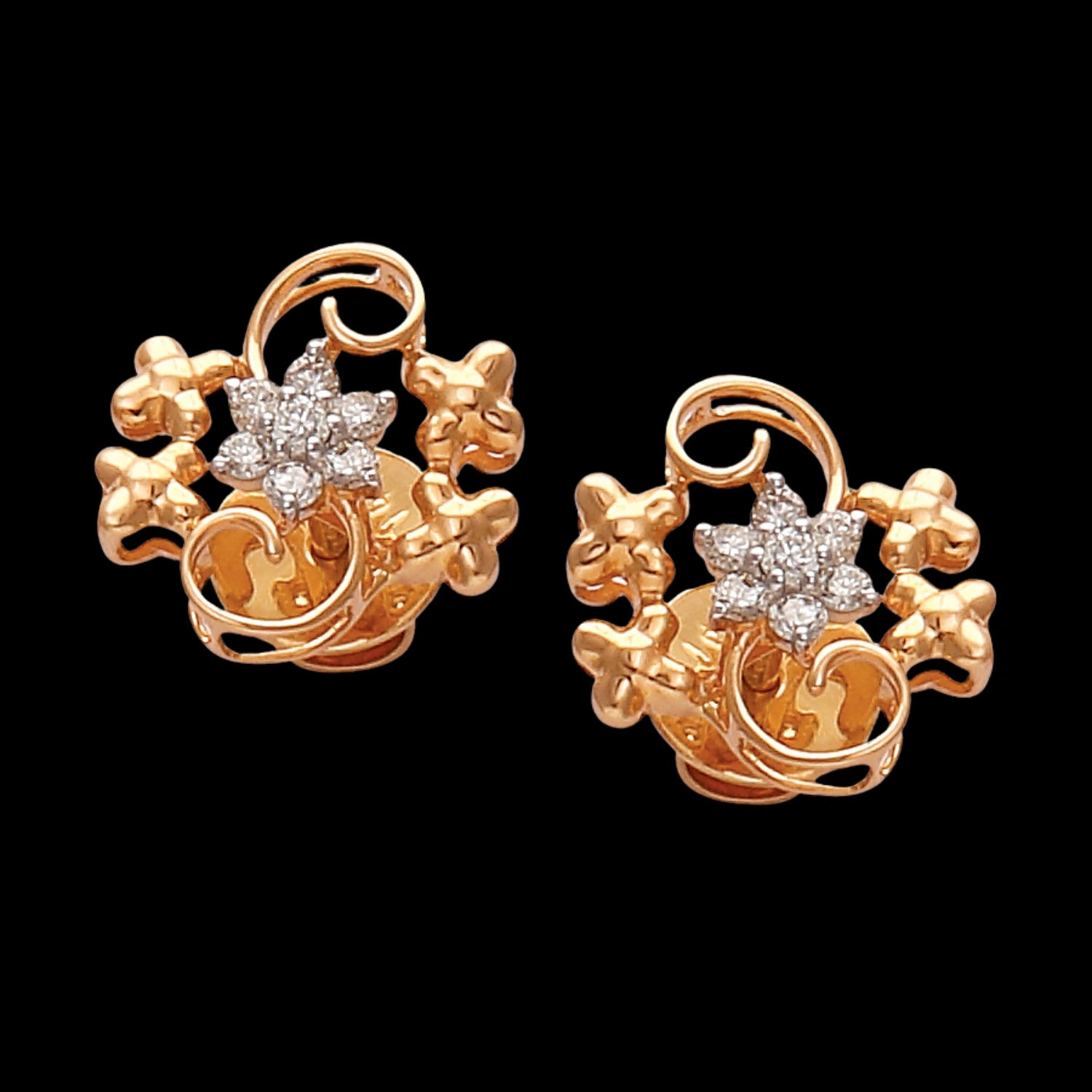 a pair of rose gold floral earrings with central diamond-like stones, surrounded by elegant vine and petal motifs on a black background — jewelry by jnjbymadhuri.
