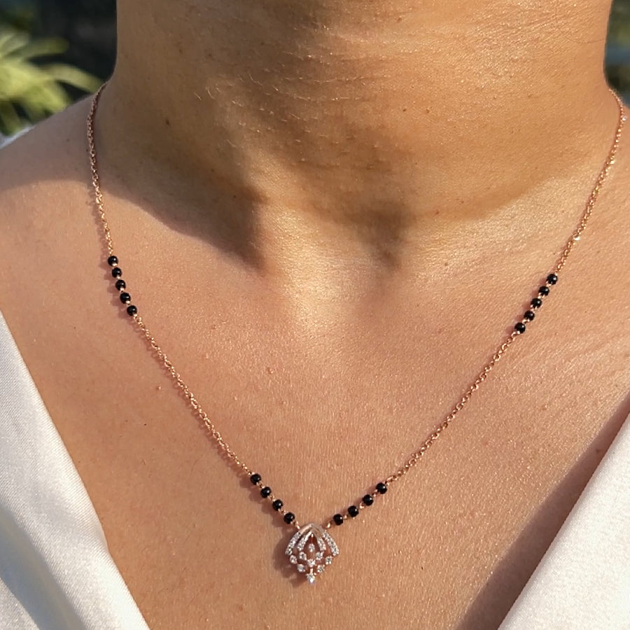 Elegant rose gold mangalsutra with delicate black beads and a sparkling diamond swirl pendant, styled gracefully on the neckline. A refined everyday piece from jnjbymadhuri.