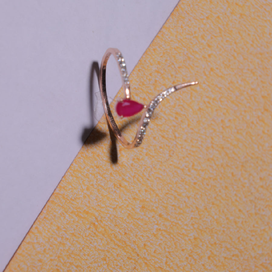 Delicate rose gold ring featuring a heart-shaped ruby centerpiece with a curved diamond-studded band. A graceful design by jnjbymadhuri.