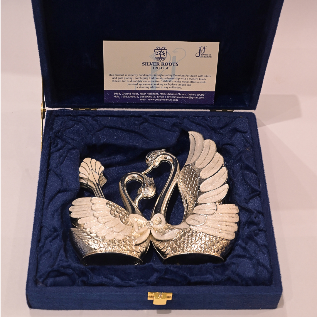 Silver swan-shaped objects in a blue box with a visible brand label.