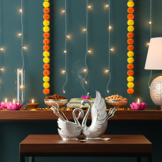 Decorative setup with swan-shaped candle holders, candles, and string lights on a dark teal wall.