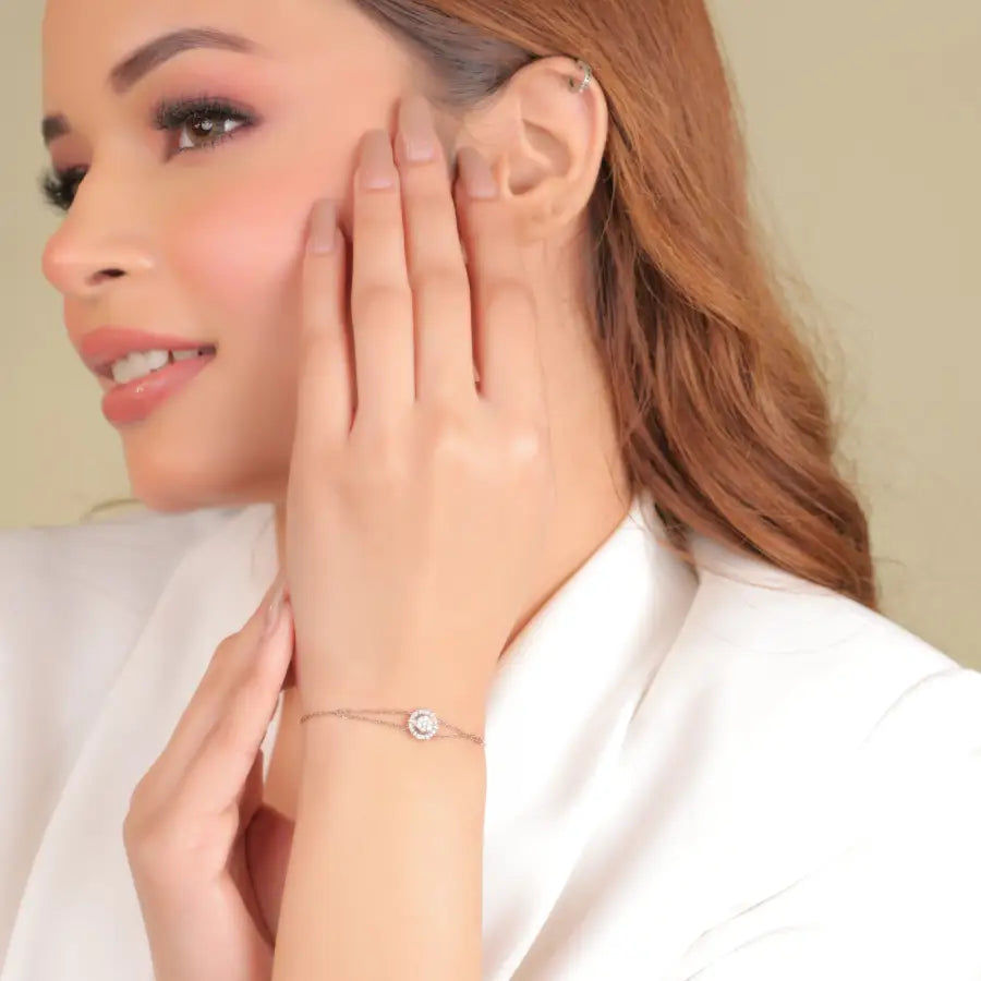 Woman wearing a delicate bracelet from jnjbymadhuri, showcasing the jewelry with a graceful hand pose and soft smile, dressed in an elegant white outfit.
