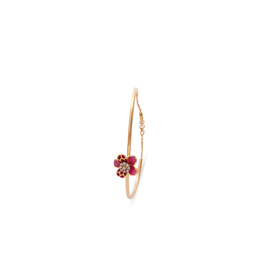 A delicate bangle by jnjbymadhuri, crafted in gold and adorned with a charming floral motif featuring rich red petals and a diamond-studded center. This elegant design blends vibrant color with timeless sparkle for a graceful, feminine touch.
