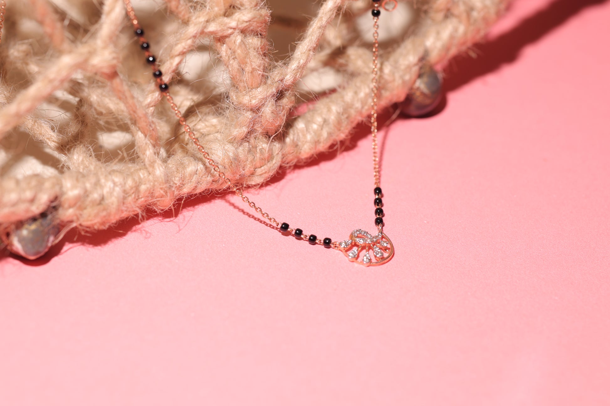 Delicate mangalsutra with a round diamond-studded floral motif, paired with fine black beads on a sleek chain. A graceful creation by jnjbymadhuri crafted for modern elegance.
