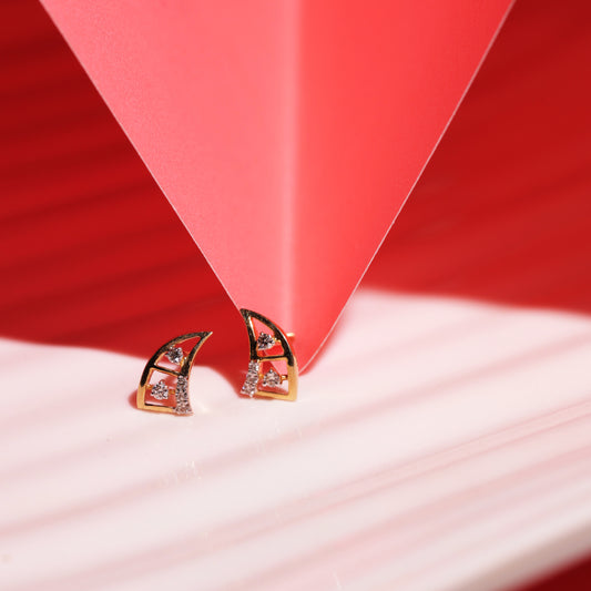 geometric gold and diamond stud earrings by jnjbymadhuri placed under a red origami-style structure, creating a dramatic shadow play on a red and white striped surface.

