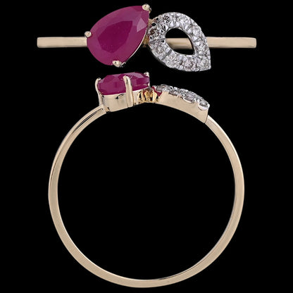 "Elegant gold ring by jnjbymadhuri featuring a pear-shaped ruby and a diamond-studded leaf design on a black background."
