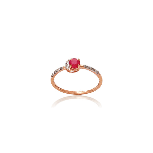 Delicate rose gold ring featuring a round red gemstone in the center, flanked by small white accent stones on a thin band, displayed on a white background with a soft reflection.
