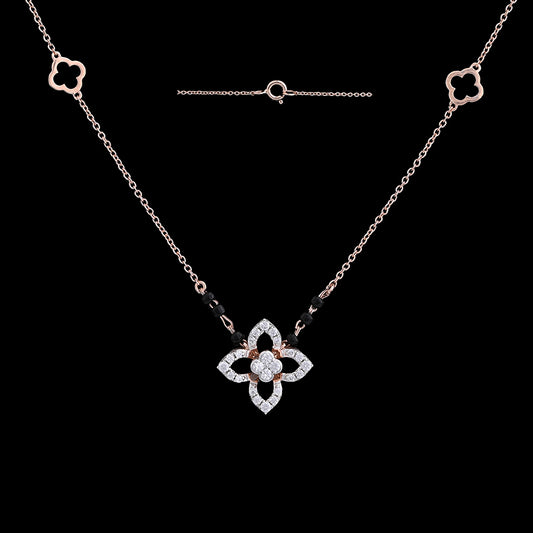 "Stylish rose gold mangalsutra necklace with a diamond-studded floral pendant and black beads, shown against a black background with matching floral motifs on the chain by jnjbymadhuri."
