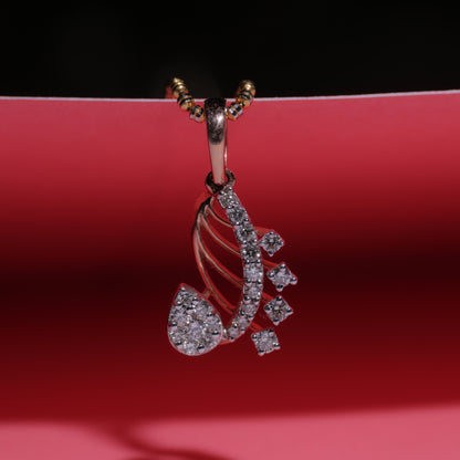 Rose gold paisley-shaped pendant by jnjbymadhuri, featuring intricate design with embedded white stones, displayed on a vibrant red background with golden chain loops.
