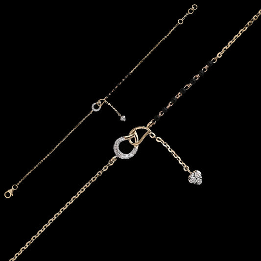Contemporary mangalsutra bracelet in dual-tone gold, featuring a circular diamond-studded charm with a dangling heart pendant and traditional black bead detailing. A chic fusion piece by jnjbymadhuri.
