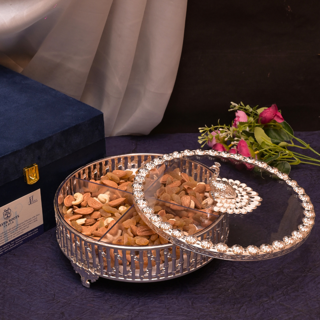 Decorative tray with nuts on a dark surface with a blue box and flowers in the background.