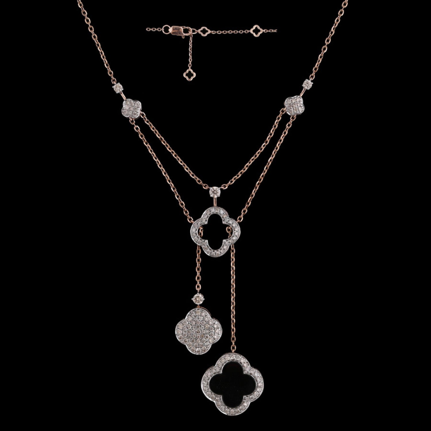 Elegant layered rose gold necklace with clover-shaped and floral diamond-studded pendants, designed by jnjbymadhuri, set against a black background.

