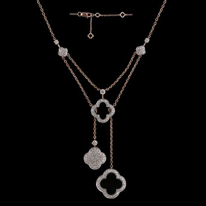 Elegant layered rose gold necklace with clover-shaped and floral diamond-studded pendants, designed by jnjbymadhuri, set against a black background.
