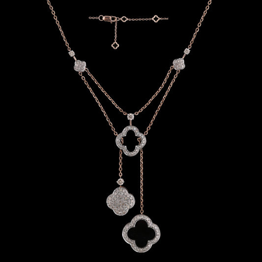 Elegant layered rose gold necklace with clover-shaped and floral diamond-studded pendants, designed by jnjbymadhuri, set against a black background.
