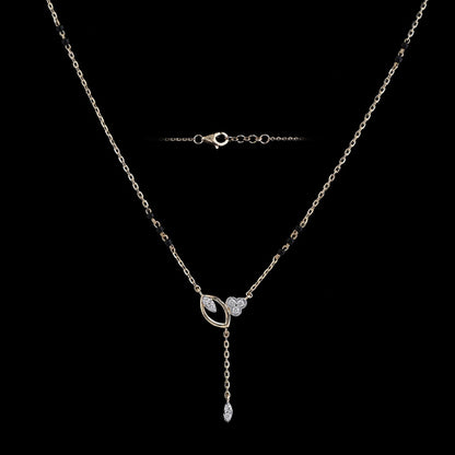 A beautifully crafted mangalsutra-style necklace with a sleek chain, black bead accents, and a modern circular pendant featuring a drop design is showcased against a black background. This elegant piece from jnjbymadhuri blends timeless charm with contemporary flair.
