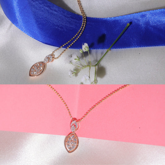 Rose gold marquise-shaped pendant necklace displayed on blue and pink satin backgrounds, featuring a central cluster of diamonds and a round diamond-studded bail, accompanied by delicate floral accents.