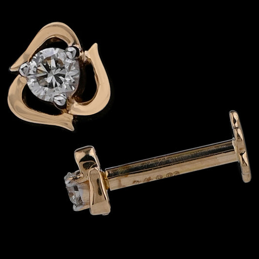 Gold stud earring featuring a heart-like openwork frame embracing a brilliant central diamond. A charming and romantic design by jnjbymadhuri.
