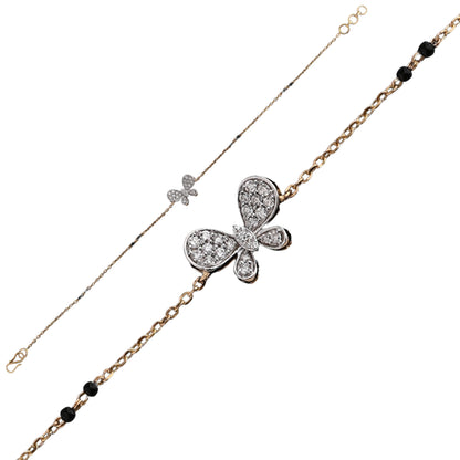 A delicate and elegant bracelet by jnjbymadhuri, featuring a charming butterfly centerpiece encrusted with sparkling diamonds. The bracelet combines a fine dual-tone chain—one side in sleek white metal and the other in warm yellow gold—accented with small black beads for a graceful contrast. This refined piece showcases intricate craftsmanship and a whimsical yet sophisticated design.
