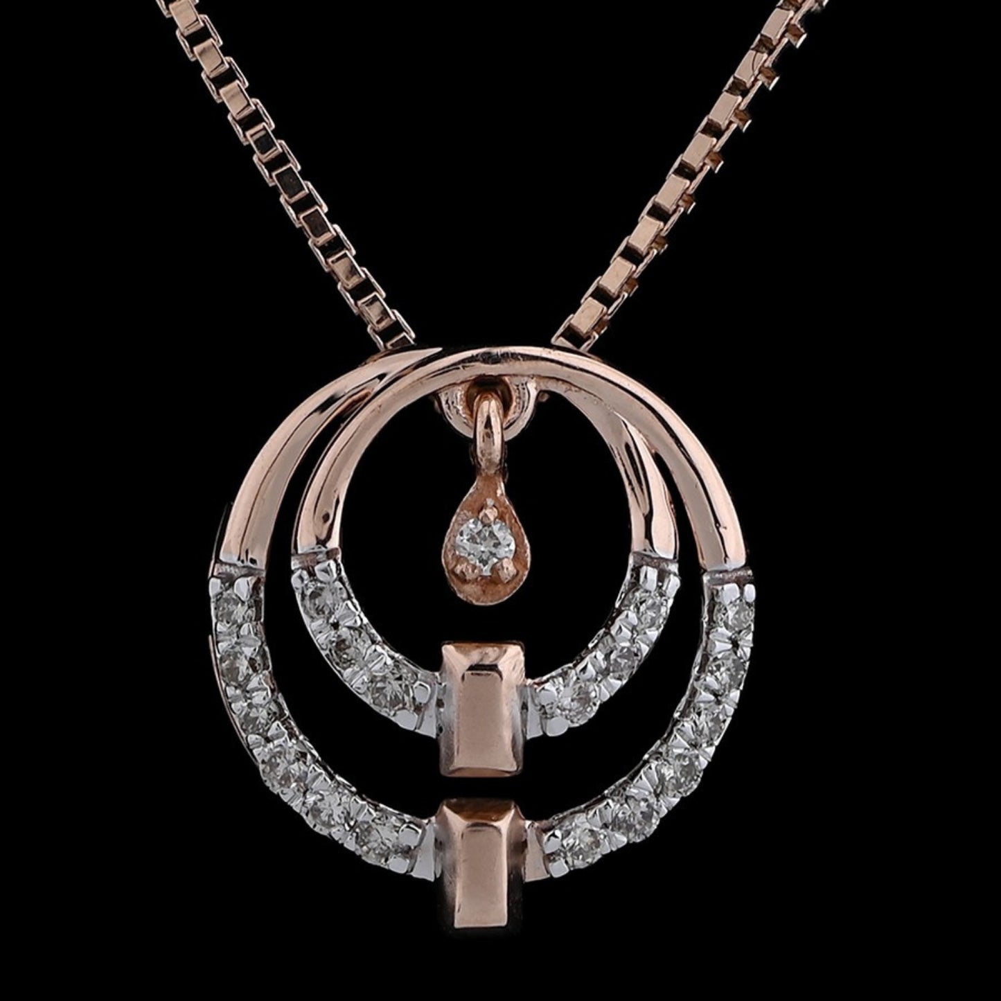 Rose gold and diamond dual-circle pendant necklace by jnjbymadhuri, featuring a teardrop detail and modern geometric elements, displayed on a dark background.
