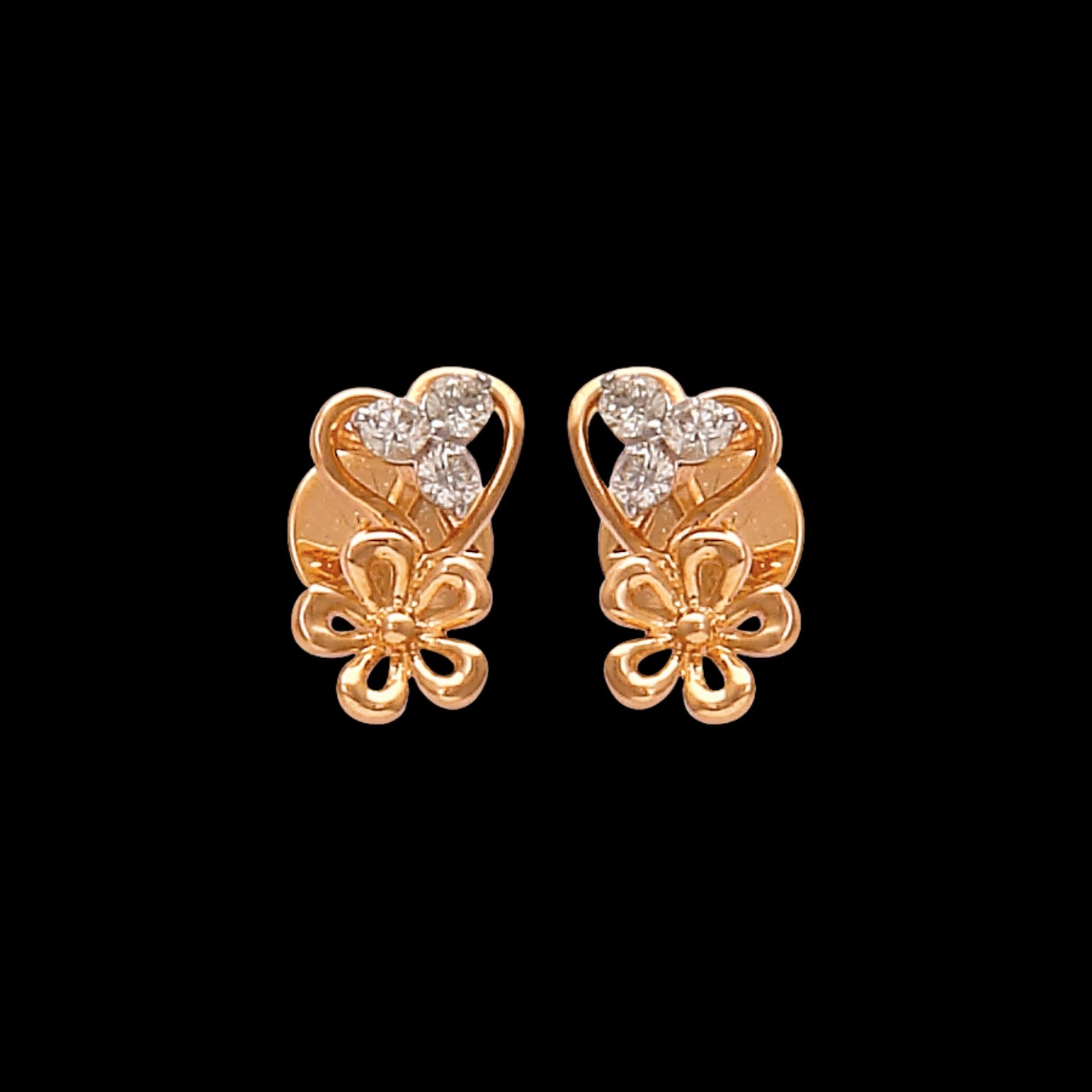 These graceful gold stud earrings by jnjbymadhuri feature a romantic heart-shaped design accented with delicate floral detailing and shimmering diamonds, blending charm and elegance in a timeless accessory.
