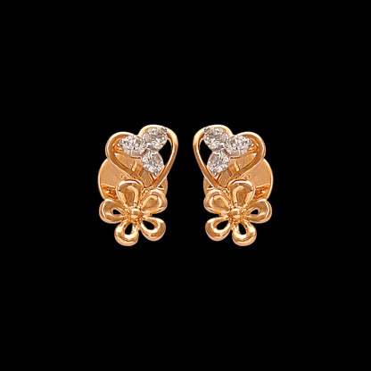 These graceful gold stud earrings by jnjbymadhuri feature a romantic heart-shaped design accented with delicate floral detailing and shimmering diamonds, blending charm and elegance in a timeless accessory.

