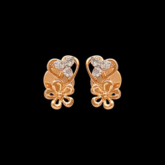 These graceful gold stud earrings by jnjbymadhuri feature a romantic heart-shaped design accented with delicate floral detailing and shimmering diamonds, blending charm and elegance in a timeless accessory.
