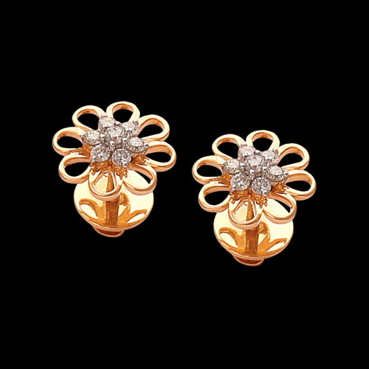 A pair of radiant floral stud earrings by jnjbymadhuri, crafted in gold with petal-like open loops and a sparkling cluster of diamonds at the center, exuding timeless elegance against a bold black background.
