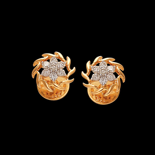 A pair of exquisite gold earrings by jnjbymadhuri, designed with intricate leaf motifs encircling a floral cluster of brilliant-cut diamonds. Set against a deep black background, the design exudes timeless elegance and showcases the brand’s craftsmanship in luxury fine jewelry.
