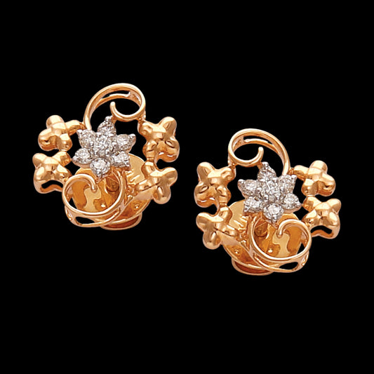 a pair of rose gold floral earrings with central diamond-like stones, surrounded by elegant vine and petal motifs on a black background — jewelry by jnjbymadhuri.
