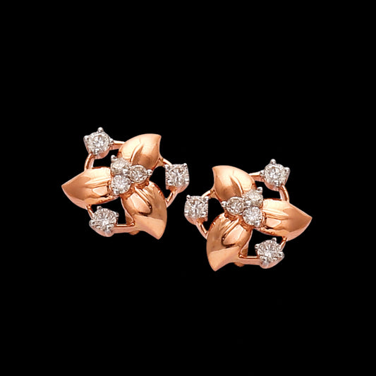 "Rose gold floral stud earrings by jnjbymadhuri, featuring petal motifs adorned with brilliant-cut diamonds, displayed against a black background for contrast."
