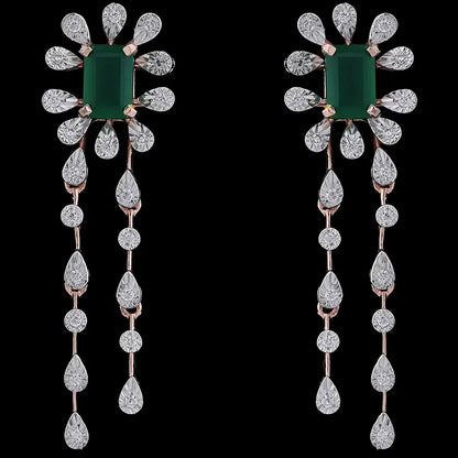 Elegant floral drop earrings featuring a central green gemstone surrounded by teardrop diamonds and twin cascading strands, set in rose gold. A luxurious statement piece by jnjbymadhuri.
