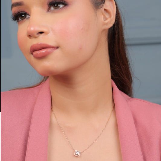 Model wearing a delicate rose gold diamond pendant necklace by jnjbymadhuri, paired with a pink blazer and natural makeup look, showcasing the elegant design of the jewelry.

