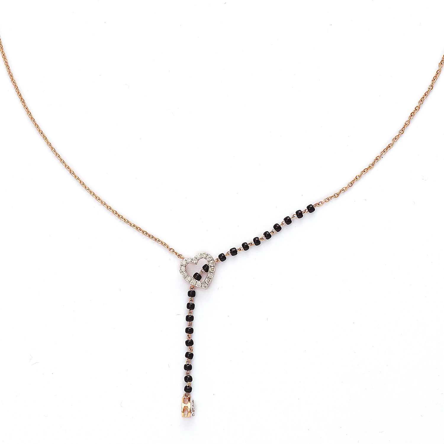 This image showcases a sleek heart-shaped mangalsutra design. It features a modern rose gold chain with a delicate black-beaded section flowing through a central, silver-tone heart charm. The heart is subtly adorned with sparkling stones, and a single drop at the end adds elegance. This piece blends contemporary aesthetics with traditional symbolism beautifully.
