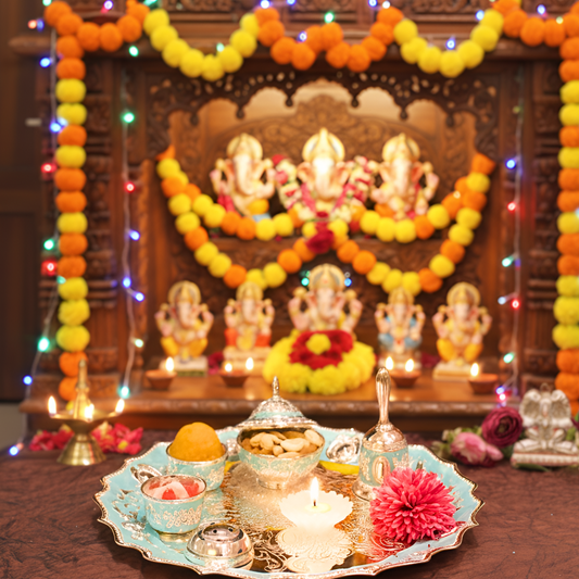 Decorative setup with lit candles, flowers, and statues in a festive setting.