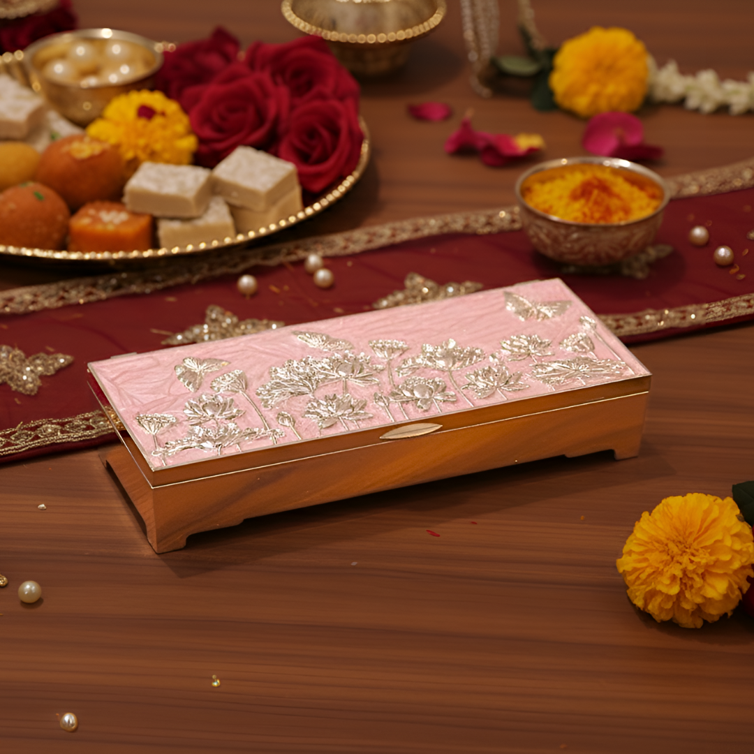 Decorative box with floral patterns on a wooden surface with flowers and sweets in the background.