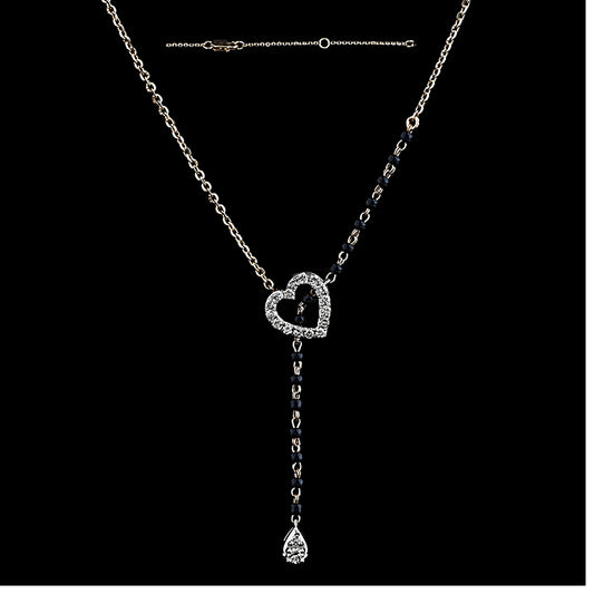 A stylish and elegant diamond heart mangalsutra by jnjbymadhuri, featuring a sparkling heart-shaped pendant encrusted with diamonds, complemented by a delicate drop-shaped diamond hanging below. The necklace combines a traditional black bead chain on one side with a sleek gold chain on the other, creating a modern, asymmetrical design perfect for contemporary Indian fashion.
